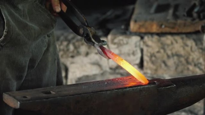 熟练的铁匠在炽热的金属坯料上用锤子敲打