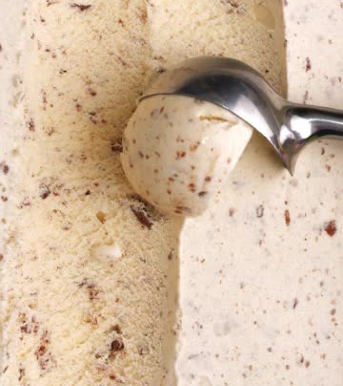 用铁勺将巧克力味的冰淇淋sc入球。