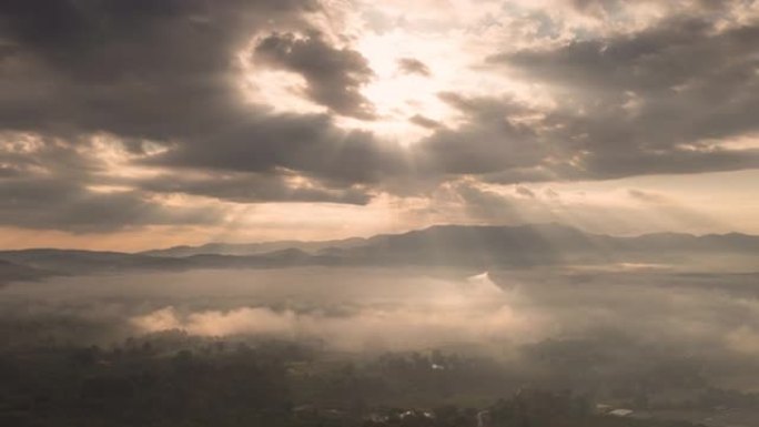 (Doi Luang Chiang Dao) 在日出时从上方观看，当光线透过雨云向下成薄雾时。