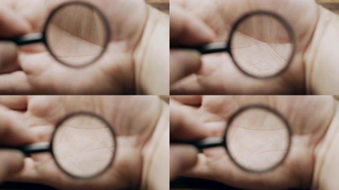一个拿着放大镜的人研究手掌上的线条和皮肤。