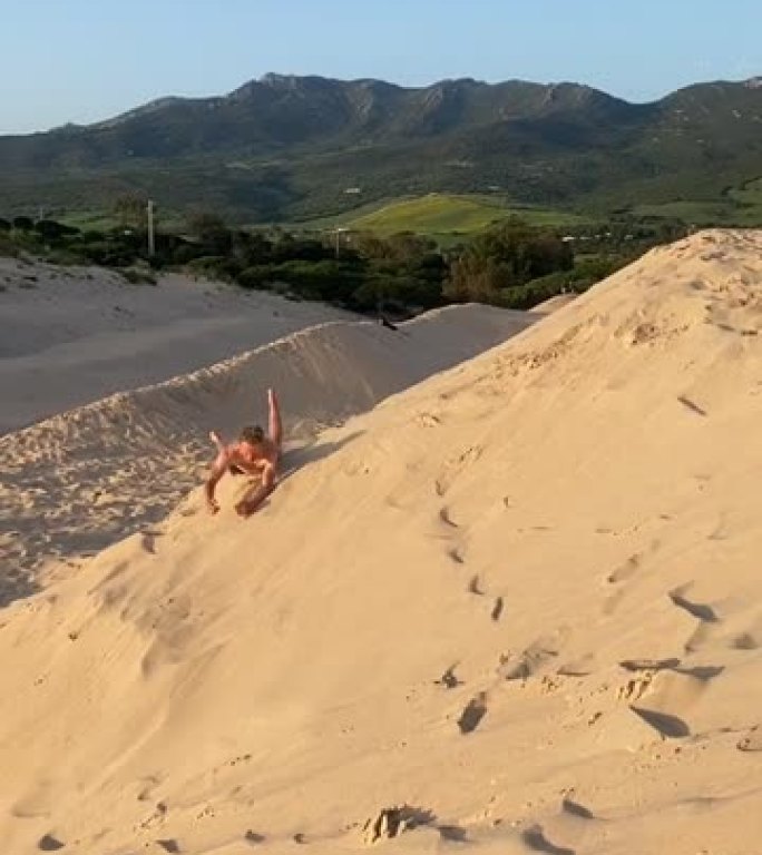 男子在沙丘上玩耍沙滩翻滚旅游区大沙包