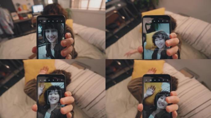 年轻女孩拍摄自己躺在床上微笑的垂直视频