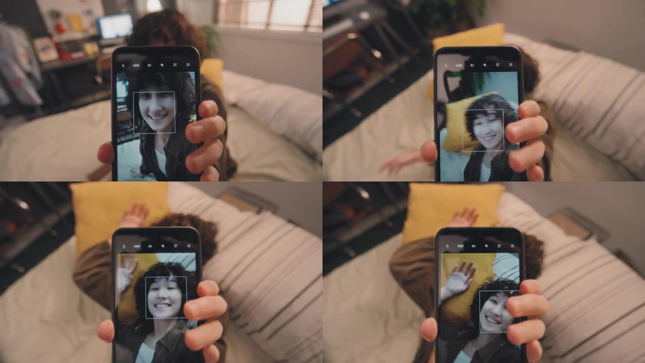 年轻女孩拍摄自己躺在床上微笑的垂直视频
