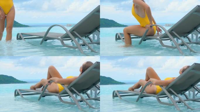 热带假日，穿着泳衣的性感女人躺在游泳池边的躺椅上