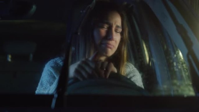 一个心烦意乱的年轻女子在雨夜坐在一辆车里，哭着抽泣。女司机对坏消息感到沮丧，情绪化，对家庭或事业问题
