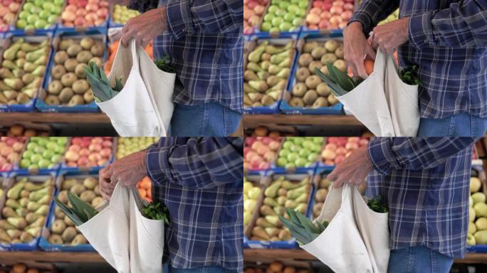 快乐的老人在当地市场商店拿着可重复使用的新鲜蔬菜袋的特写镜头-可持续的零浪费食品零售