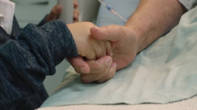 小男孩抱着祖母的手奶奶躺在医院的病床上，孩子在床边对从疾病中康复的祖父母表示爱意。医疗保健家庭支持