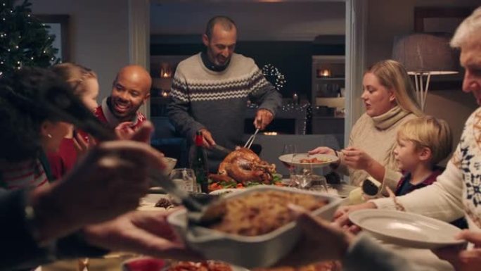 家庭圣诞晚餐男子切火鸡在节日庆祝会上供应美味的饭菜人们坐在餐桌旁享受美味的盛宴在家庆祝节日4k镜头