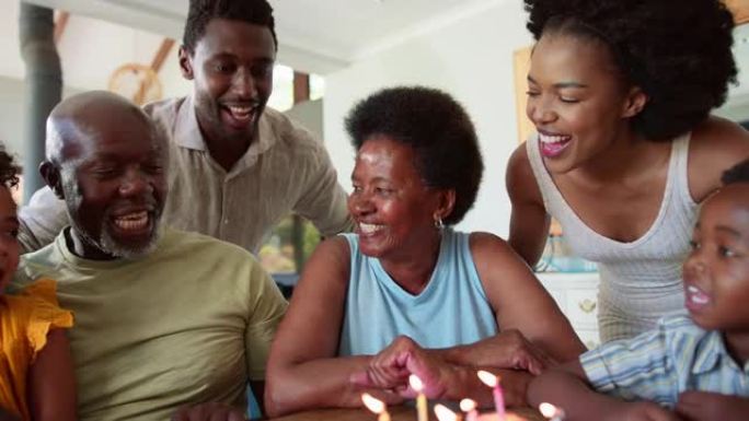 多代家庭在家中餐桌旁用蛋糕和蜡烛庆祝祖母的生日