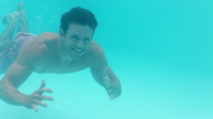 迷人的年轻人在游泳池水下游泳挥手微笑快乐漂浮在清澈的水中玩得开心夏季游泳4k