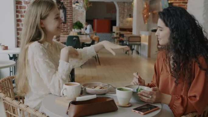 展示订婚戒指的年轻女子在咖啡馆午休时与朋友分享好消息