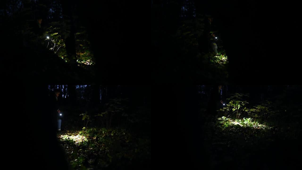 在夜林里拿着手电筒的女人。穿过黑暗的森林。