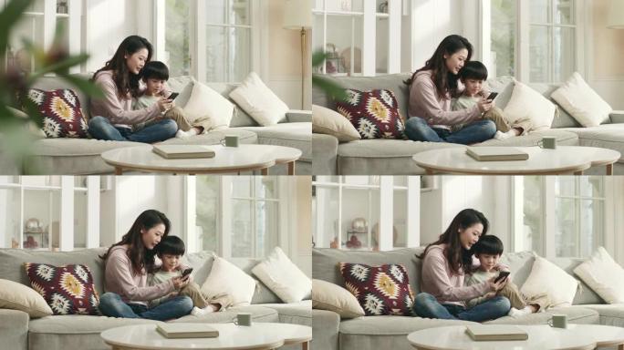 年轻的亚洲母亲和儿子在家里一起看手机