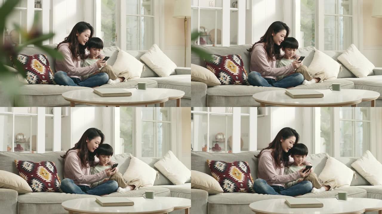 年轻的亚洲母亲和儿子在家里一起看手机
