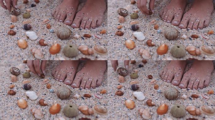 特写脚女人在海滩上收集贝壳，享受美丽的自然品种，在沙滩上塑造图案