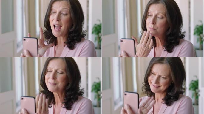 聋哑妇女手持智能手机进行视频聊天，使用手语聋哑祖母挥舞着享受手机上的连接聊天