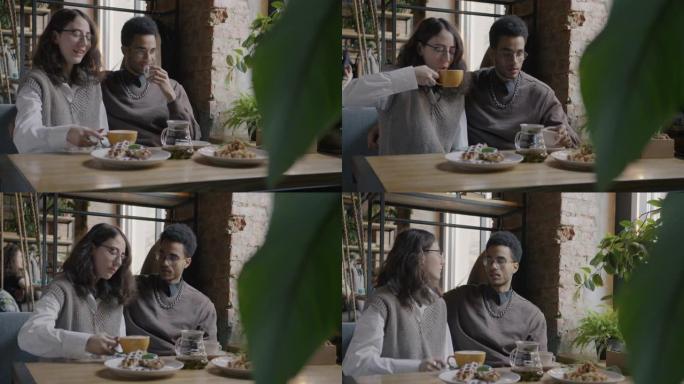 快乐的年轻人的肖像男人和女人在咖啡馆的餐桌上喝咖啡和聊天放松