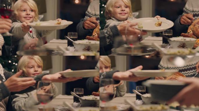 可爱的小男孩享受圣诞夜晚餐与家人一起吃美味的家常便饭传递盘子分享节日盛宴在家4k镜头