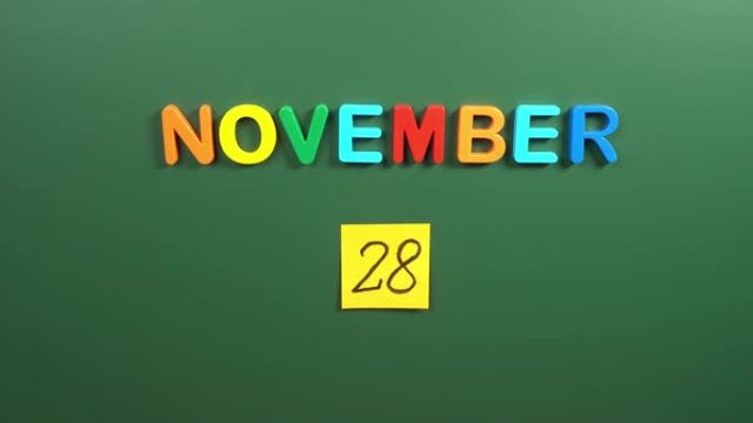 11月28日日历日用手在学校董事会上贴一张贴纸。28 11月日期。11月第二十八天。第28个日期号。