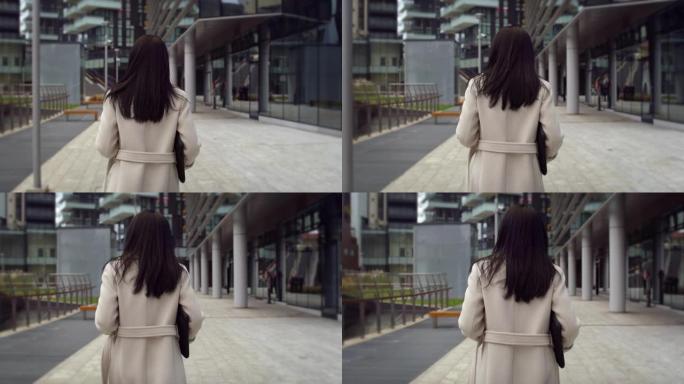 优雅的女商人在早晨走向办公室的背影。女项目经理走在街上，准备开始一天的工作，为公司会议考虑创新的想法