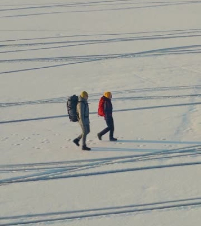 两个旅行者在空旷的雪场中漫步