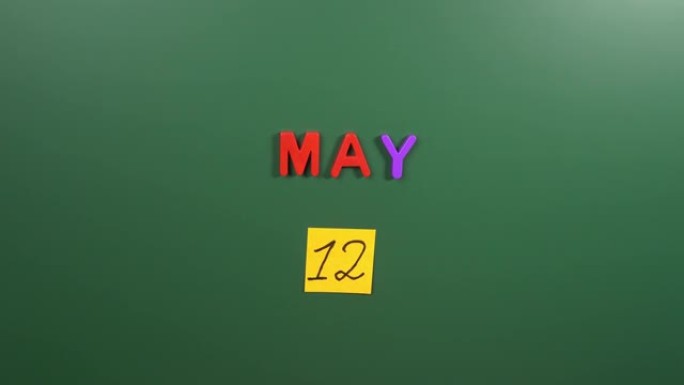 5月12日日历日用手在学校董事会上贴一张贴纸。5月12日。五月的第十二天。第12个日期编号。12天日