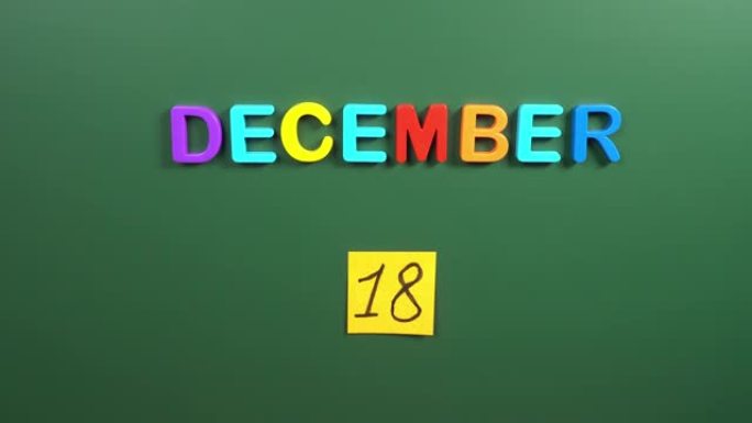 12月18日日历日用手在学校董事会上贴一张贴纸。18 12月日期。12月的第十八天。第18个日期编号