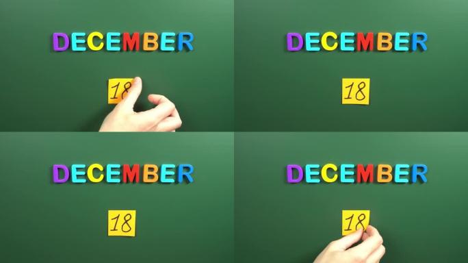 12月18日日历日用手在学校董事会上贴一张贴纸。18 12月日期。12月的第十八天。第18个日期编号
