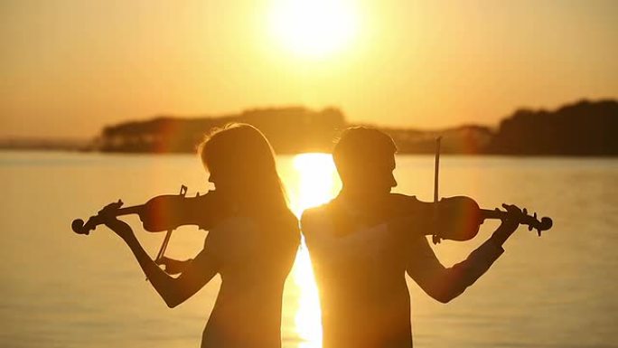 小提琴二重唱男女在日落时演奏小提琴