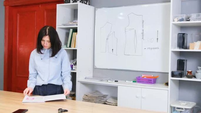 一位年轻的时装设计师女孩进行缝纫衣服和内衣的培训，并在板上绘制图案