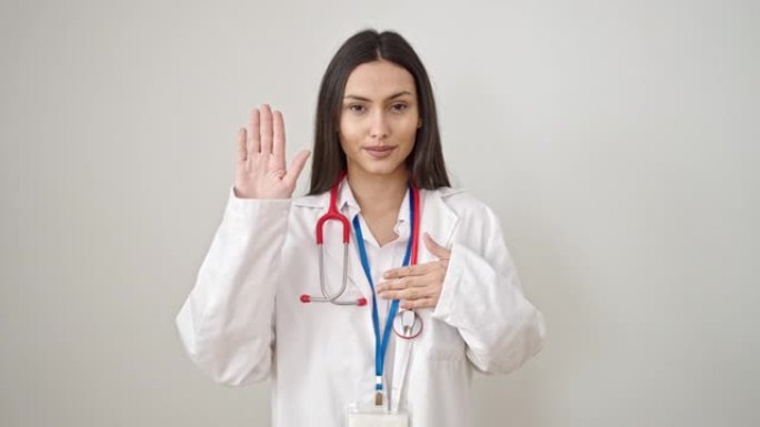 年轻美丽的西班牙裔女医生用手在孤立的白色背景上发誓