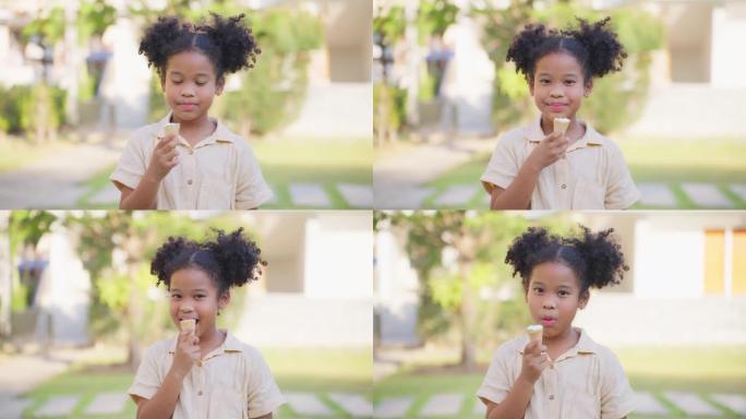 非裔美国小女孩在花园里吃冰淇淋的肖像。年轻可爱的孩子站在户外，拿着甜蜜的甜点，微笑着，看着相机，感到