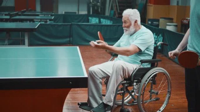 坐在轮椅上的激动老人微笑着在俱乐部打乒乓球