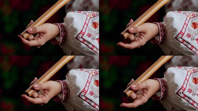 在木管乐器木笛上演奏的女人之手-深色背景上的乌克兰telenka或tylynka。民间音乐概念。乐器