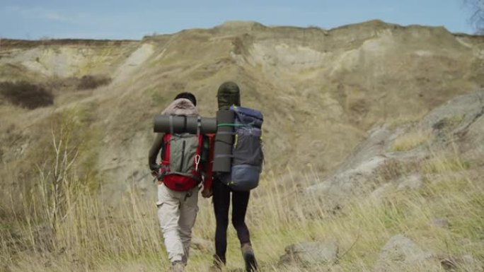 两个朋友牵着手，在岩石基地徒步旅行，荒芜的岩石景观