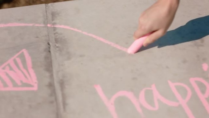 女人用粉红色粉笔在地面上书写幸福的少女享受创造力