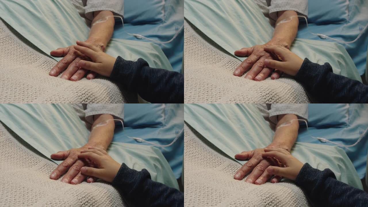 小男孩触摸祖母的手躺在医院的病床上，孩子在床边对奶奶从疾病中康复表示爱意。