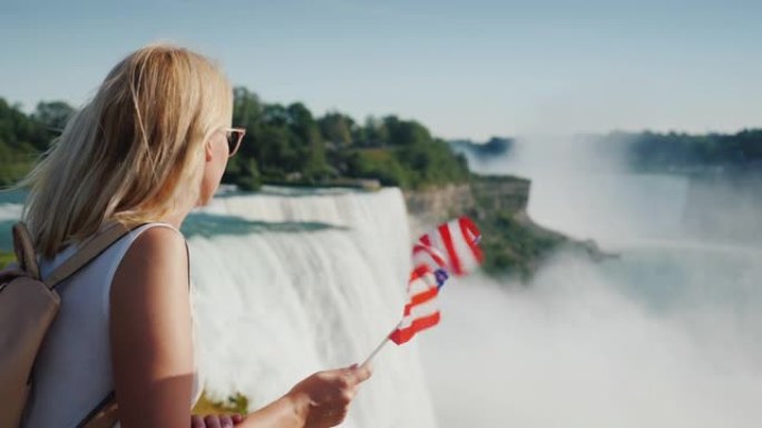 手持美国国旗的游客站在河的美国一侧欣赏尼亚加拉大瀑布