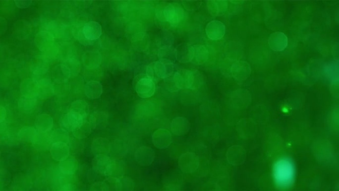模糊的绿色闪光颗粒在黑色背景下在空中飞行