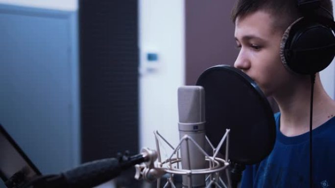 录音棚会议: 十几岁的男孩在唱片公司的麦克风前录制自己的声音