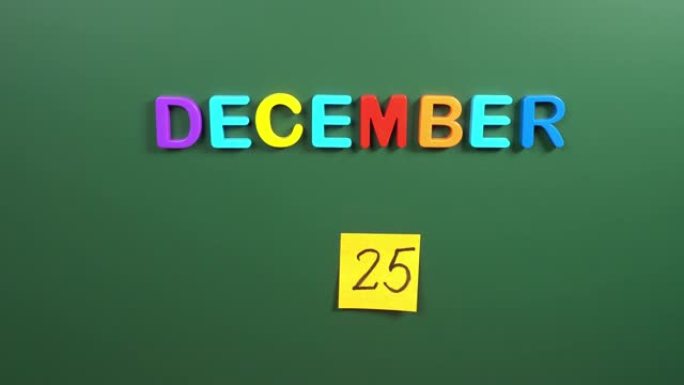 12月25日日历日用手在学校董事会上贴一张贴纸。25 12月日期。12月第二十五天。第25个日期编号