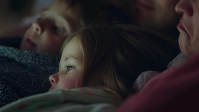 使用平板电脑的幸福家庭父母喜欢在触摸屏技术上与孩子们一起观看娱乐节目，睡前放松