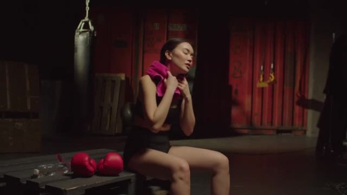 疲惫的运动型适合亚洲女拳击手在健身房训练后脱下拳击手套