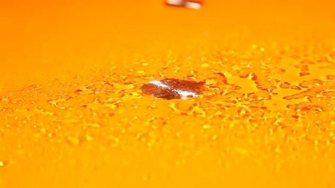 在橙色表面上喷洒水滴
