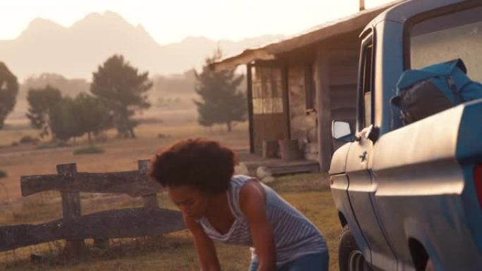日落时分，微笑的女人从卡车上卸下背包，前往乡村的小木屋——用慢镜头拍摄