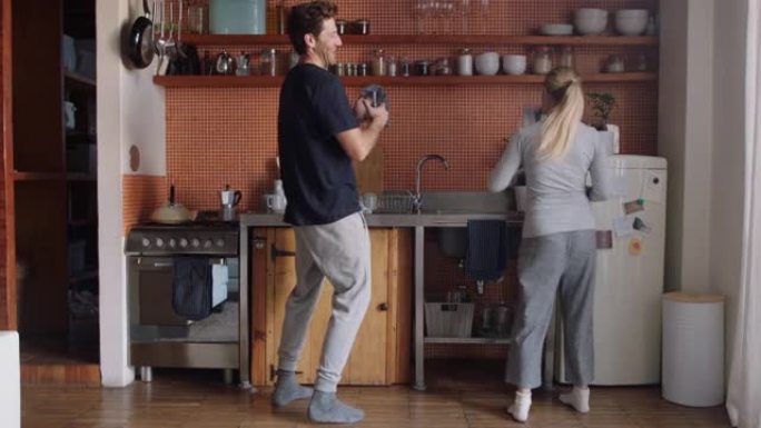 快乐的年轻夫妇在厨房跳舞，一起享受有趣的舞蹈，周末在家庆祝关系