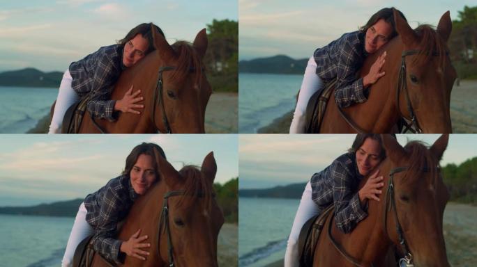 日落时在海边海滩上骑马的美女肖像。职业女性马术在看海的同时拥抱和爱抚着她的纯种马。自由概念