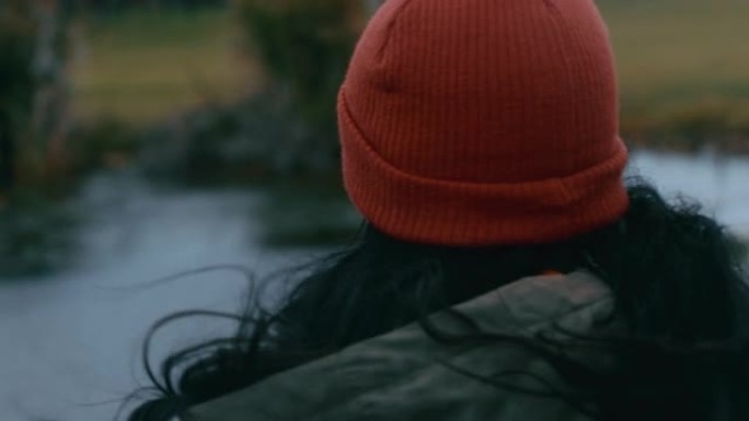 孤独的年轻女子穿着红色豆豆在公园散步享受大自然少女在阴天感到沮丧风吹着头发