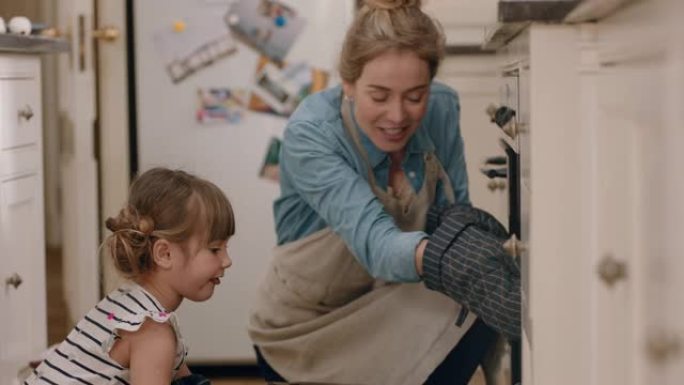 快乐的小女孩帮助妈妈在厨房烘烤，带着自制的纸杯蛋糕从烤箱里拿出来，戴着烤箱手套，享受新鲜美味的食物