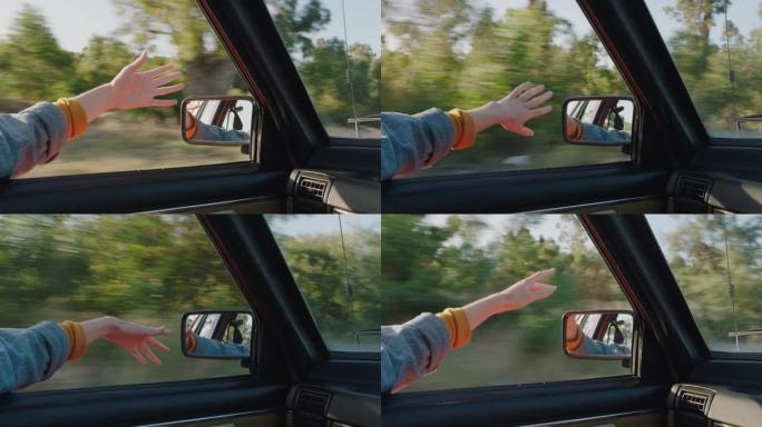 女人牵着手走出车窗，感觉风吹过手指，在乡下开车，暑假旅行，享受路上的自由